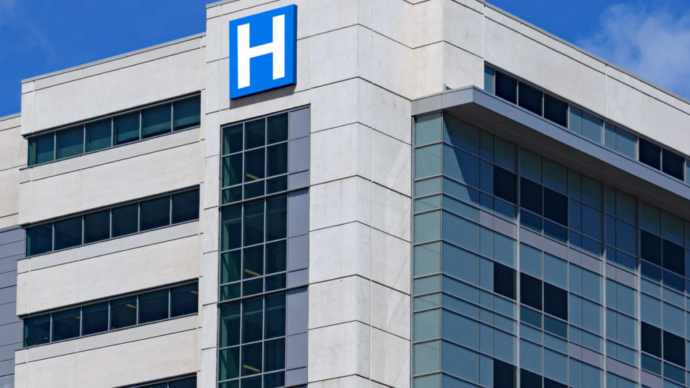 large modern building with blue letter H sign for hospital