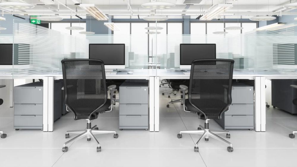 Social Distancing in Modern Office. Office Desk With Glass Partition Dividing Them Social Distancing in Modern Office. Office Desk With Glass Partition Dividing Them
