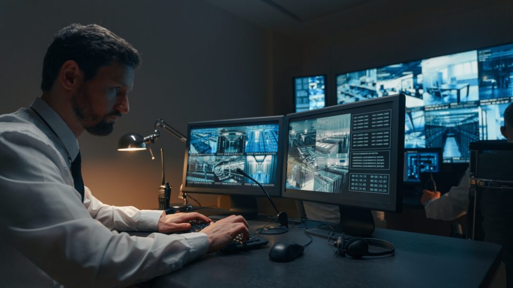 Security guards monitoring modern CCTV cameras indoors Man working within a government SCIF, with extra privacy through sound masking