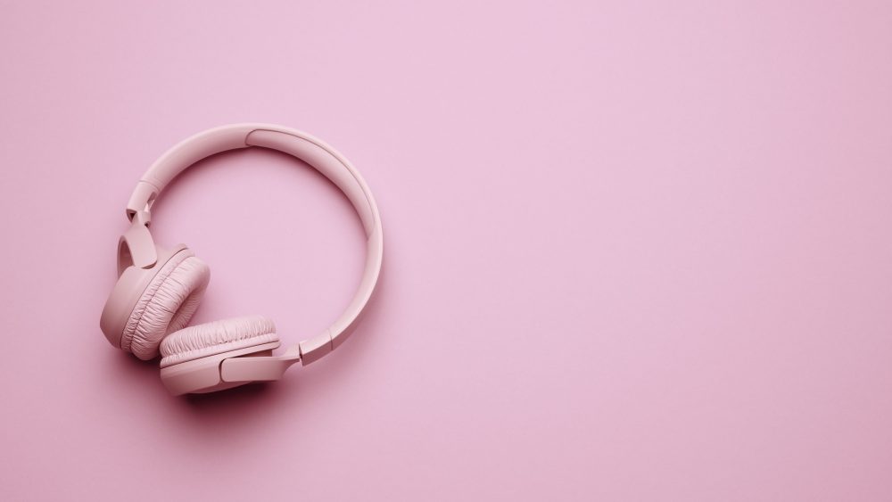 pink wireless headphones on a pink background, banner. Top view on modern gadget pink wireless headphones on a pink background, banner. Top view on modern gadget, place for an inscription