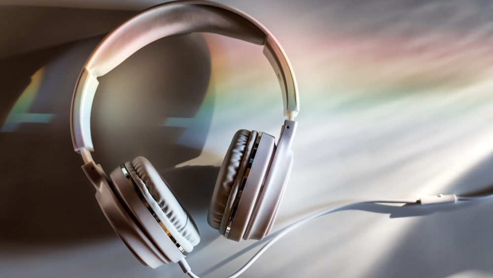 White Headphones On A White table in the evening light White Headphones On A White table lit by a sunset light dispersed into rainbow. Headphones at the office desk top at the end of the day