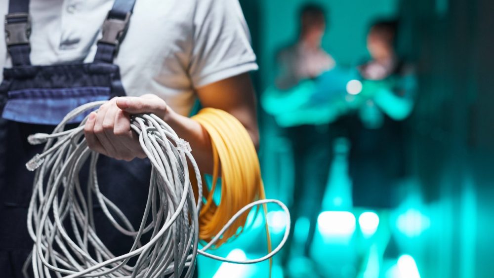 Close up of network engineer holding cables in server room during maintenance work in data center, copy space